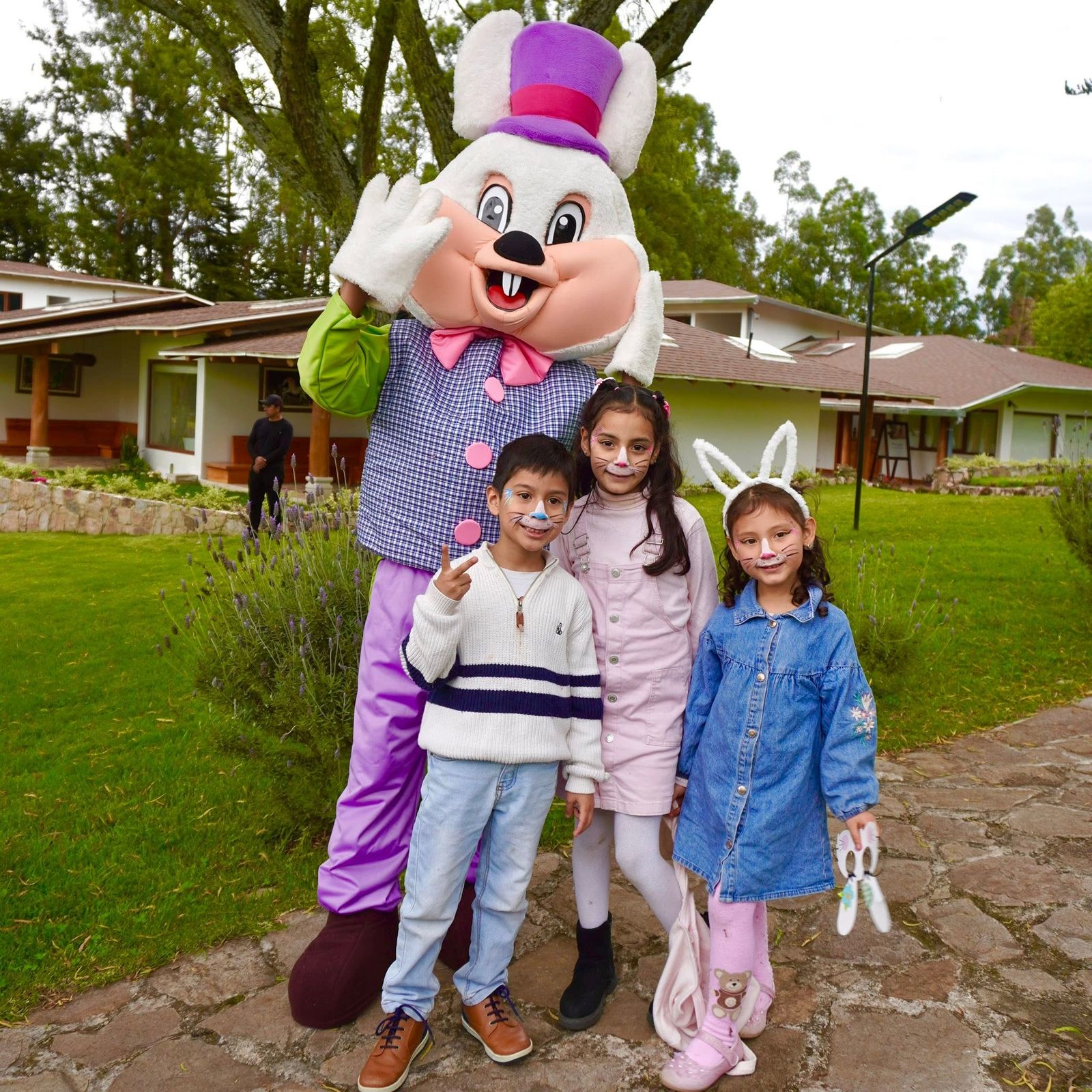 Mascota de conejo junto a niños con caritas pintadas